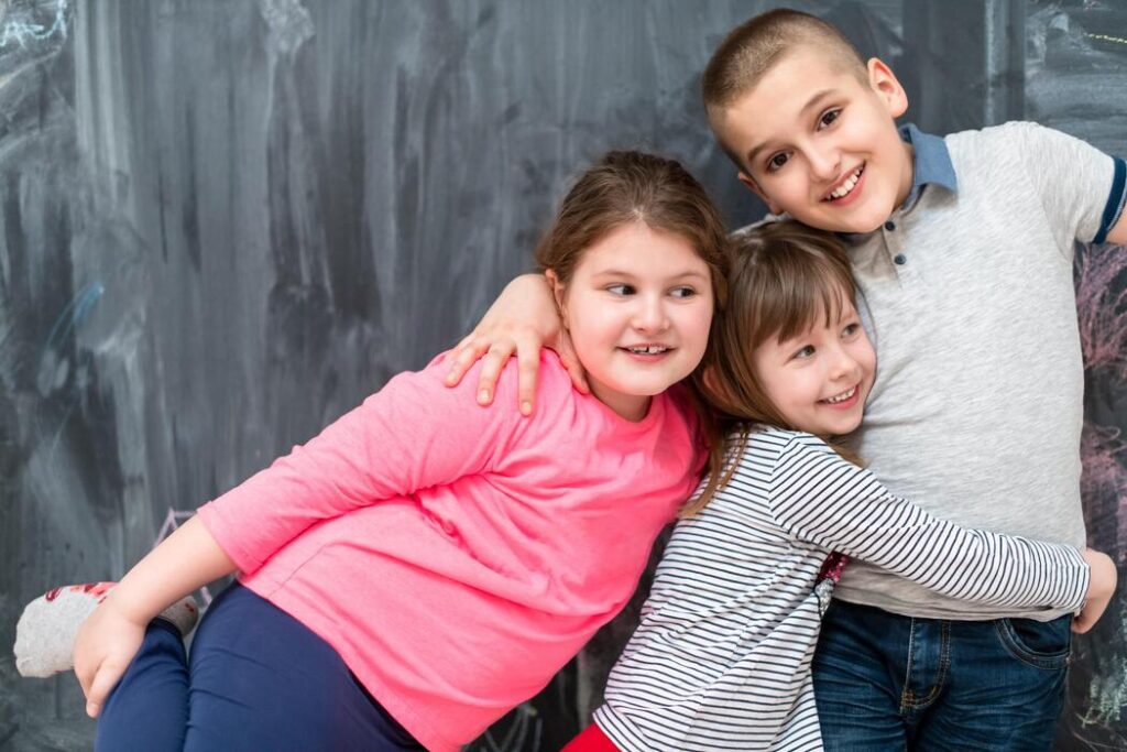 Group of children hugging in front of a chalkboard